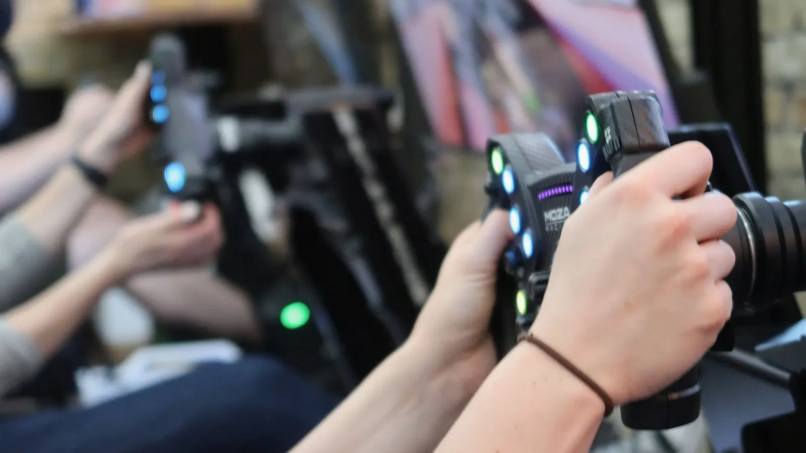 A guest grips an illuminated racing wheel on a Skid Mark simulator